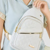 Un sac bandoulière matelassé gris clair est porté par une personne vêtue d'une chemise bleu clair.