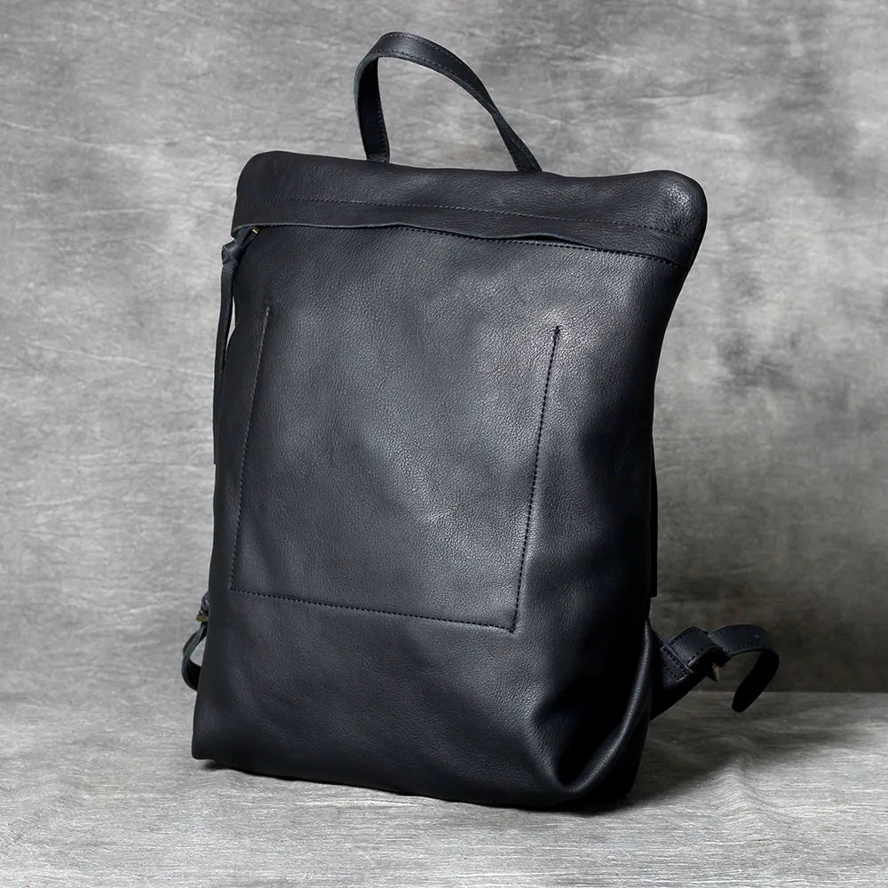 A black genuine full-grain leather backpack is shown against a gray background.
