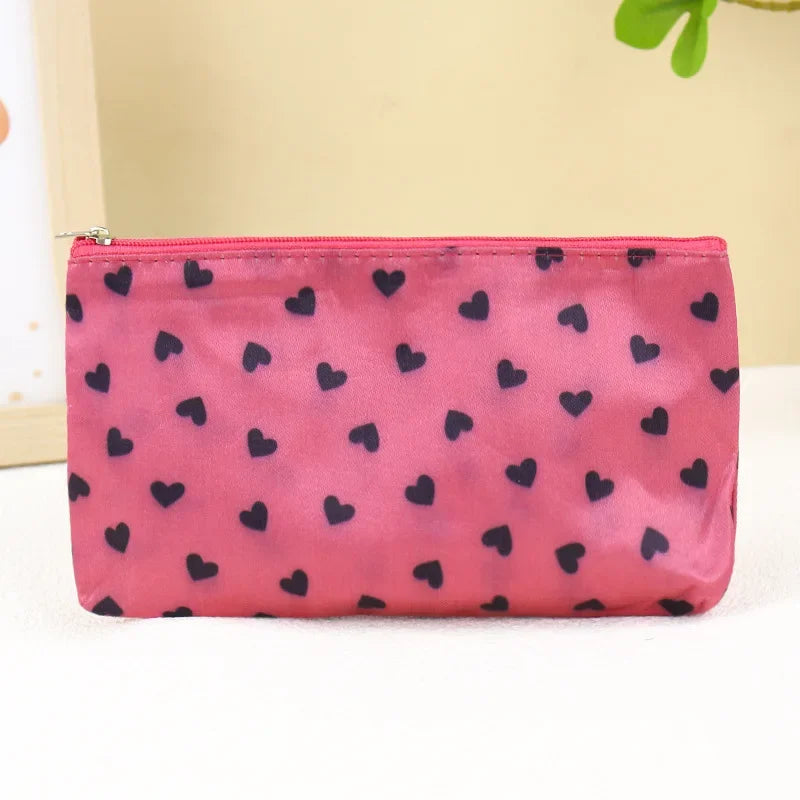 A pink cosmetic bag with a leopard print pattern and a zipper, lying on a white surface.