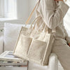 Un sac fourre-tout beige clair en velours côtelé à rayures verticales porté par une femme à l'intérieur.