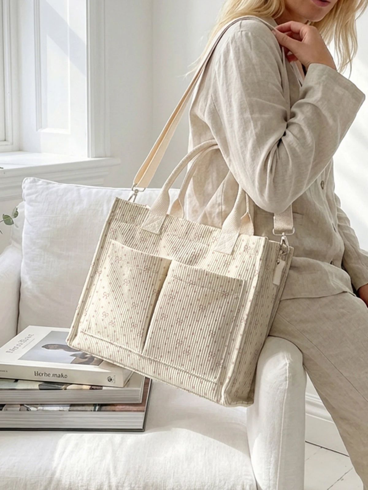 Un sac fourre-tout beige clair en velours côtelé à rayures verticales porté par une femme à l'intérieur.
