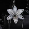 Silver realistic orchid flower keychain attached to a black leather bag.