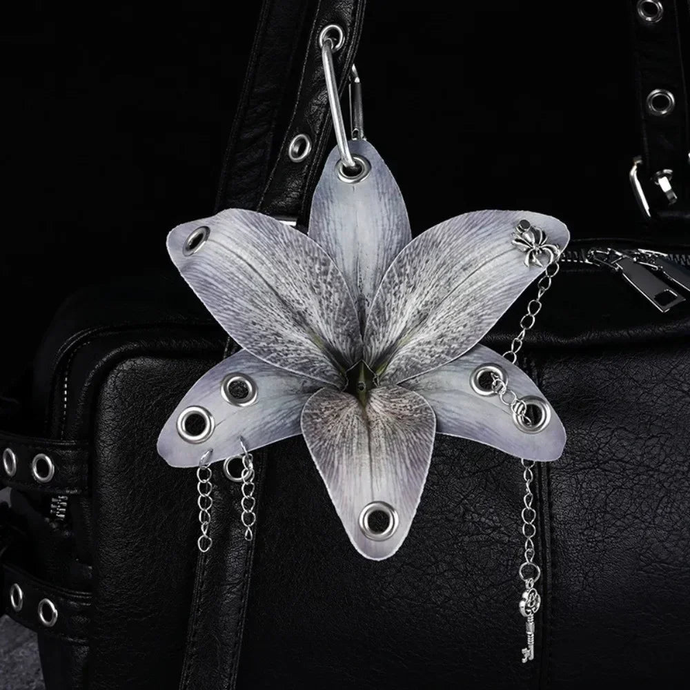 Silver realistic orchid flower keychain attached to a black leather bag.