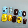 A set of press-on nails featuring various colors and designs including blue, brown, yellow, and light blue with cartoon chara
