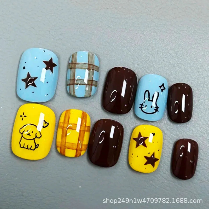 A set of press-on nails featuring various colors and designs including blue, brown, yellow, and light blue with cartoon chara