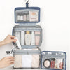 A blue toiletry bag with a hanging hook is shown open, displaying various skincare and cosmetic products.