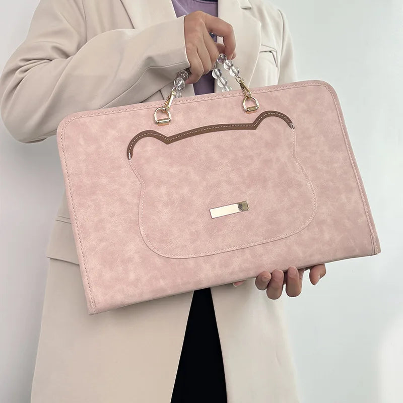 A woman holds a pink leather laptop sleeve with gold hardware and a brown stitched design.