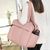 A woman is carrying a large pink travel duffle bag over her shoulder.