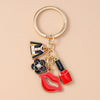 A gold-toned enamel heart keychain featuring a black and white design with a flower and lips.