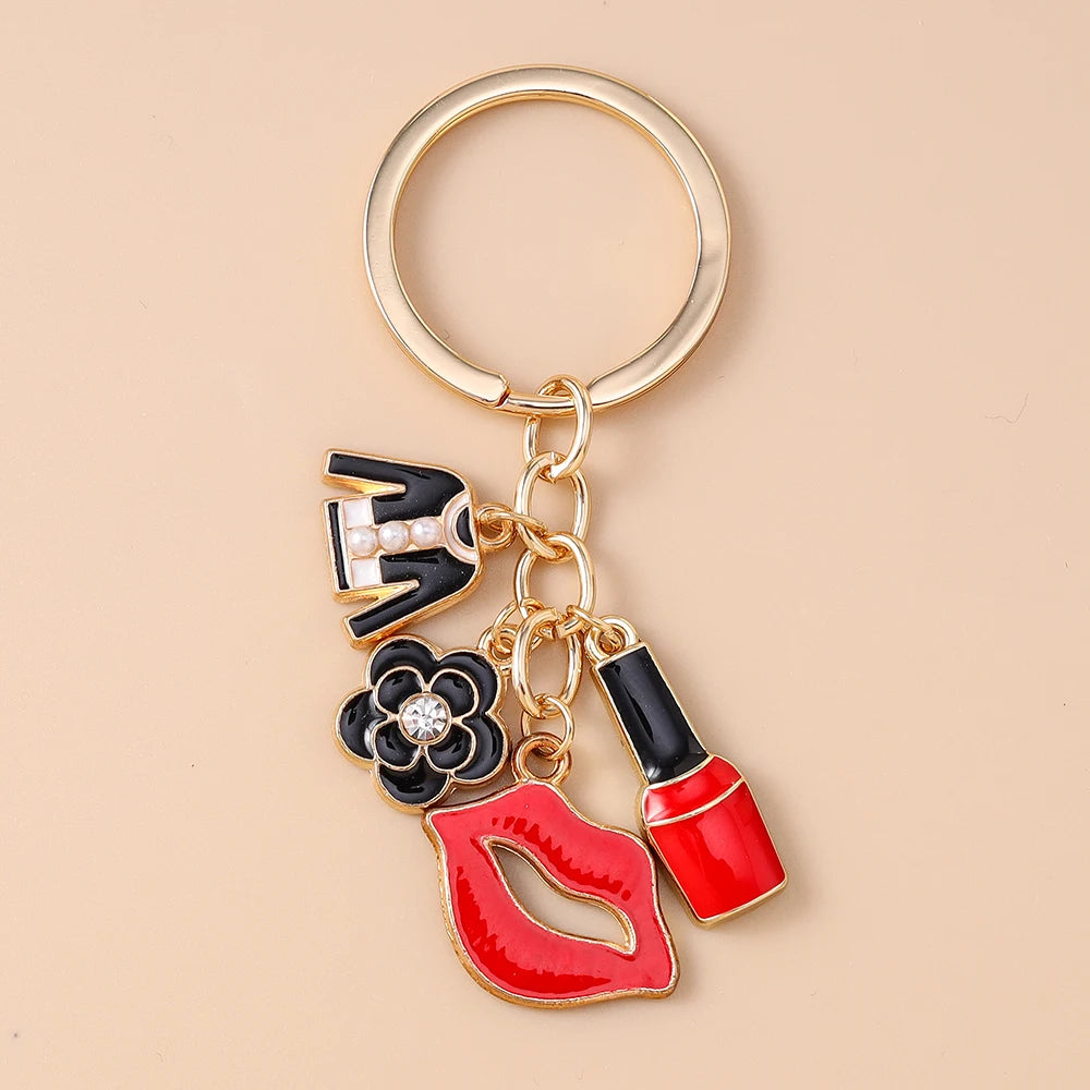 A gold-toned enamel heart keychain featuring a black and white design with a flower and lips.