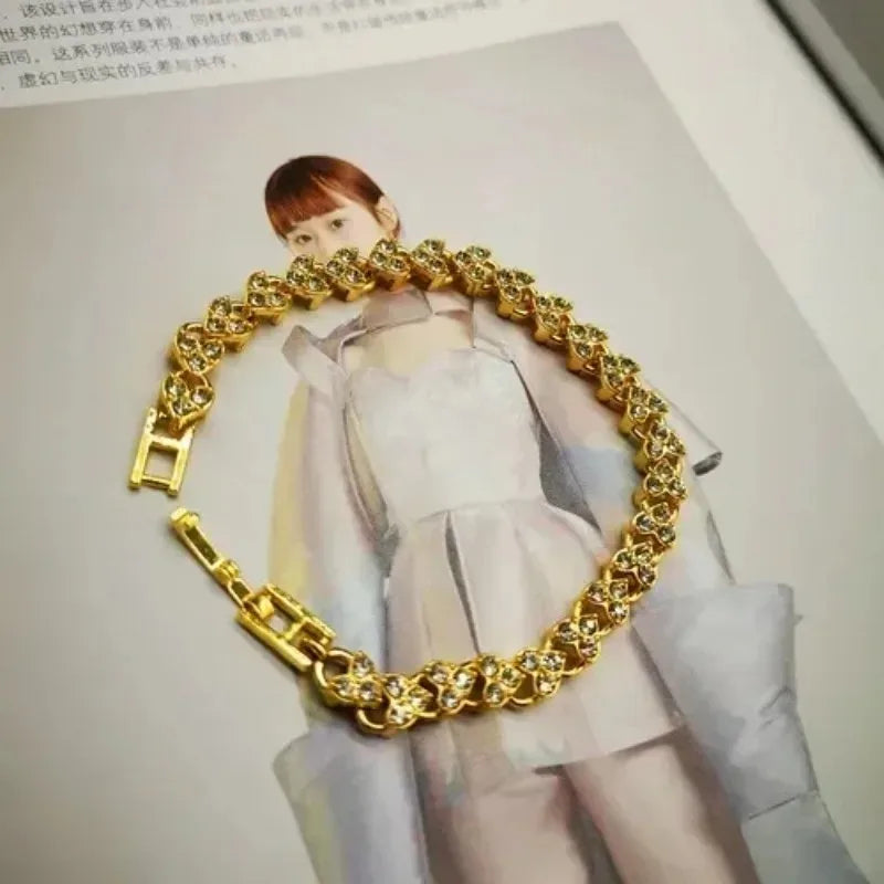 A close-up of a gold stainless steel charm bracelet featuring a portrait pendant.