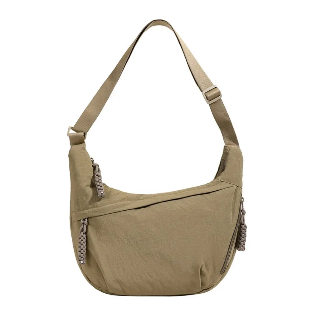 A tan canvas crossbody bag with a drawstring closure is shown against a white background.