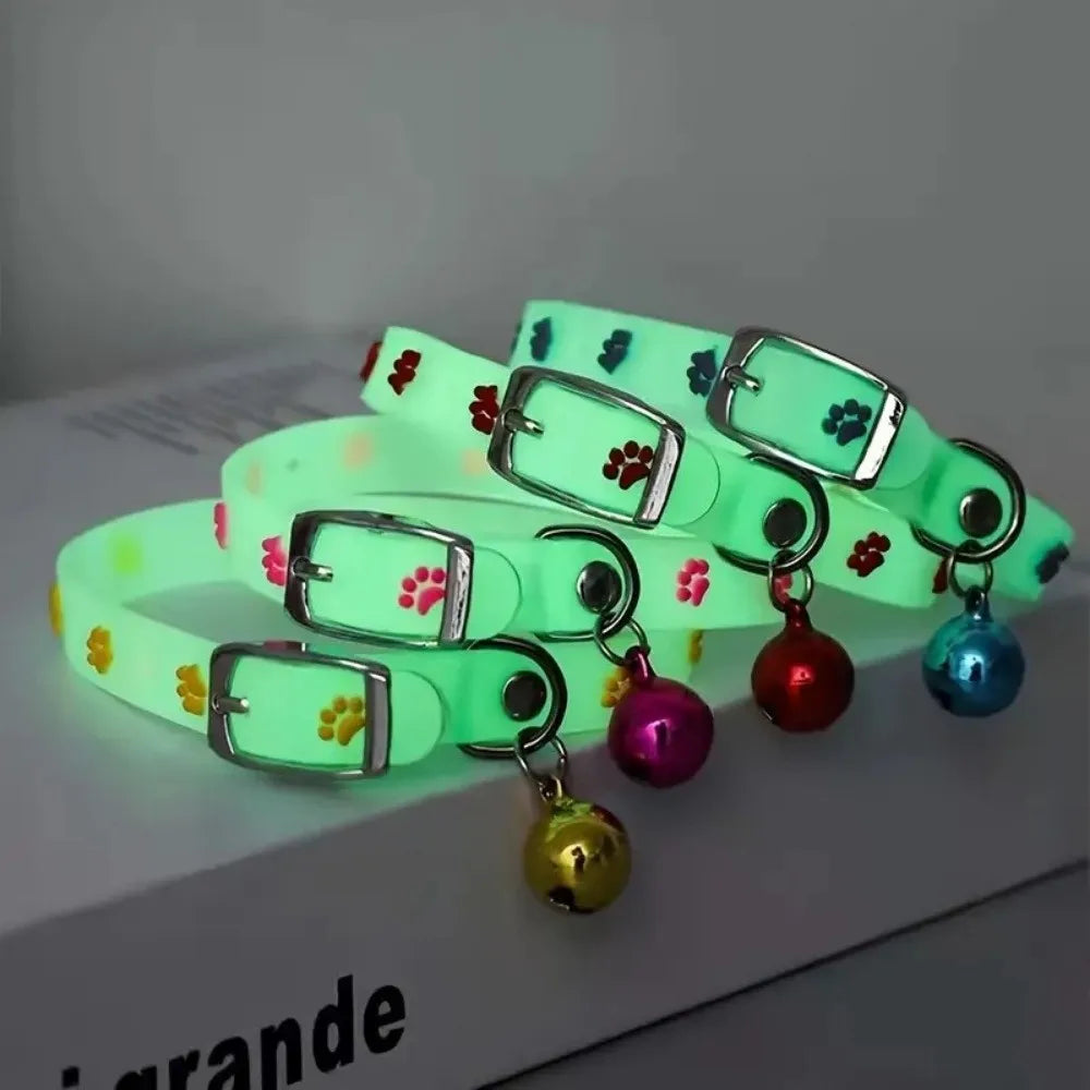 A set of glow-in-the-dark pet collars for dogs and cats in various shades of green and pink resting on a white surface.