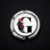 Silver foldable letter hanger hook with a decorative floral design on the surface