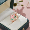 A delicate rose gold butterfly ring featuring pink and green enamel set in a velvet jewelry box.