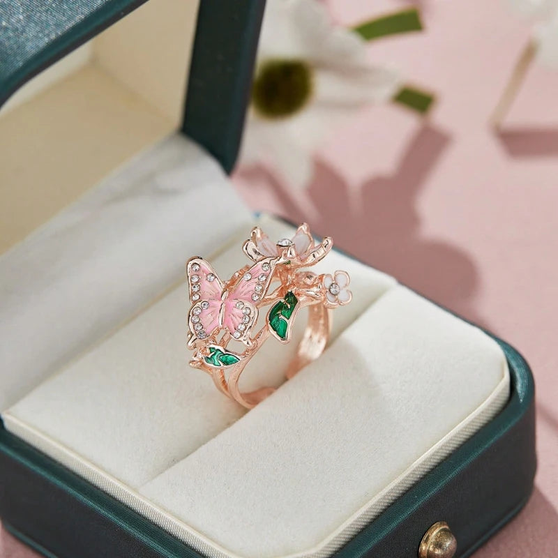 A delicate rose gold butterfly ring featuring pink and green enamel set in a velvet jewelry box.