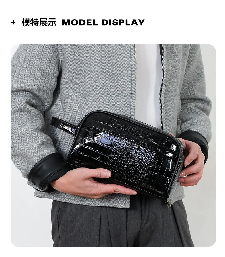 A black crocodile print clutch bag is displayed in a model's hand against a gray blazer.