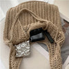 A beige knit shoulder bag with a bohemian texture is displayed on a white surface, featuring a black accessory.