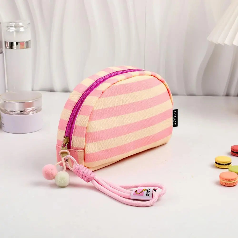 Pochette en crochet rayée rose et blanc avec fermeture éclair violette et cordon rose.