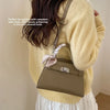 A woman models an elegant brown PU leather crossbody clutch bag paired with a cream sweater and white skirt.