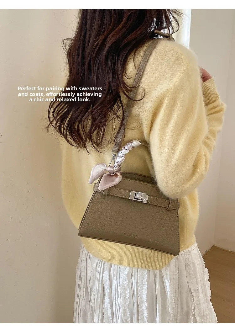 A woman models an elegant brown PU leather crossbody clutch bag paired with a cream sweater and white skirt.