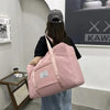 A person is holding a pink canvas travel storage bag with multiple compartments in front of a wall display.