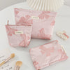 Pink bow knot cosmetic organizer bags and a large pink paper fan on a white surface.