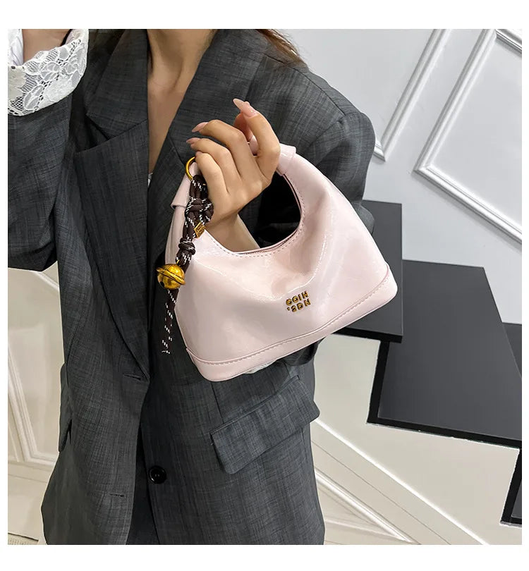 A light pink retro PU leather shoulder bag with a gold chain strap is shown being held by a woman wearing a gray blazer.