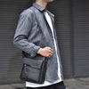 Un homme portant une chemise rayée tient un sac à bandoulière noir en PU.