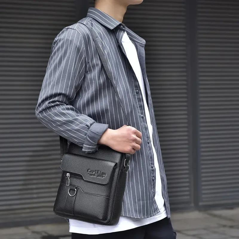 Un homme portant une chemise rayée tient un sac à bandoulière noir en PU.