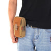 A brown tactical belt pouch with a leather flap and clip is shown attached to the waistband of blue jeans.