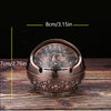 A vintage metal ashtray with a rose embossing design and windproof lid shown on a wooden surface.