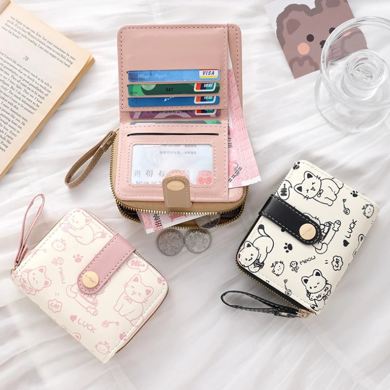 A pink cat cartoon coin purse and card holder wallet with various cards and coins displayed on a white surface.