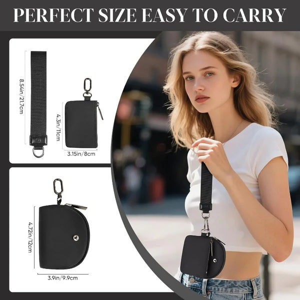 A woman holds a black dual-zip wristlet wallet with a detachable strap in daylight.