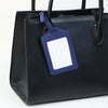 A black PU leather handbag with a dark blue luggage tag attached to the strap.