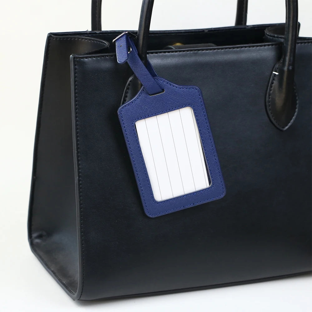 A black PU leather handbag with a dark blue luggage tag attached to the strap.