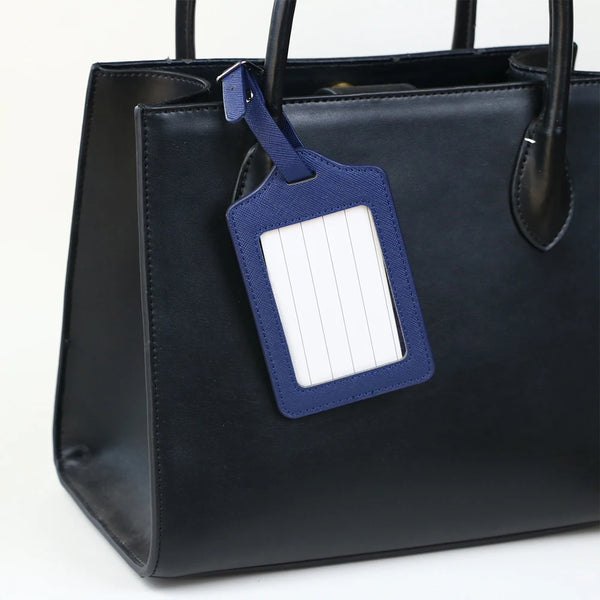 A black PU leather handbag with a dark blue luggage tag attached to the strap.