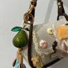 A crystal fruit charm keychain featuring a green pear hanging from a leather strap.