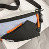 A black nylon chest rig bag with orange accents and a black strap is shown lying on a white surface.