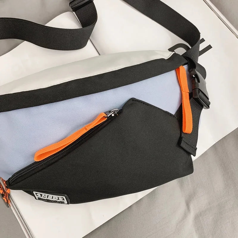 A black nylon chest rig bag with orange accents and a black strap is shown lying on a white surface.