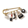 Gold-toned alloy brooch pin featuring a black and white design with pearl accents.