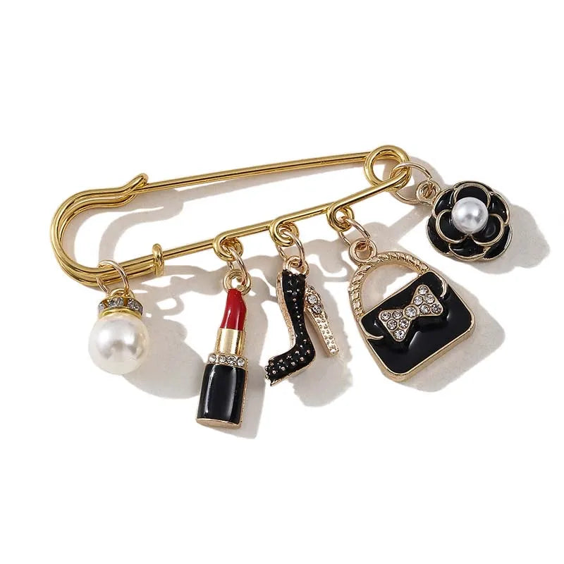 Gold-toned alloy brooch pin featuring a black and white design with pearl accents.