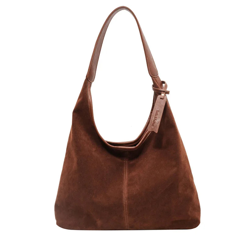 A brown suede slouchy shoulder bag with a leather strap is shown against a white background.