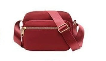 A maroon compact oxford fabric crossbody bag with a strap shown from the front.