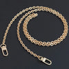 A gold-colored adjustable metal chain strap for a crossbody bag, laid out on a dark surface.