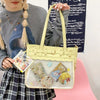 A person holds a light yellow Y2K punk goth crossbody bag with decorative charms against a dark background.