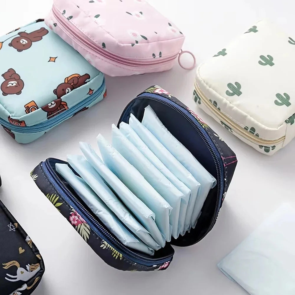 A collection of pink, mint green, and white portable waterproof sanitary napkin storage pouches are displayed on a white surf