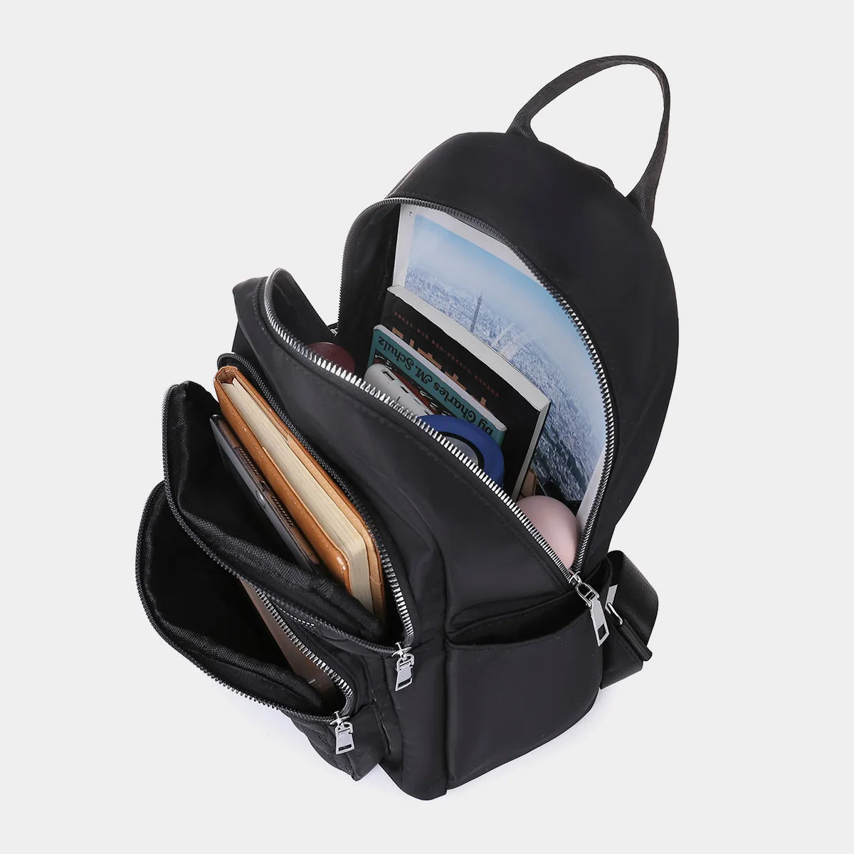 A black waterproof women's travel backpack with a zippered compartment open, showing various items inside.