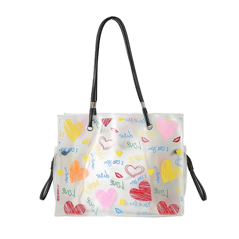 A clear plastic face mask with pink and yellow hearts printed on it, featuring black ear loops.