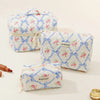A set of quilted cotton makeup organizers in white with pink and blue floral patterns.